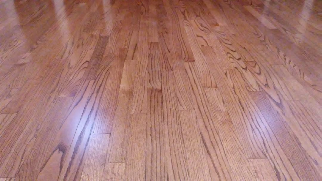 Shiny hardwood floor with natural wood grain patterns and warm tones.