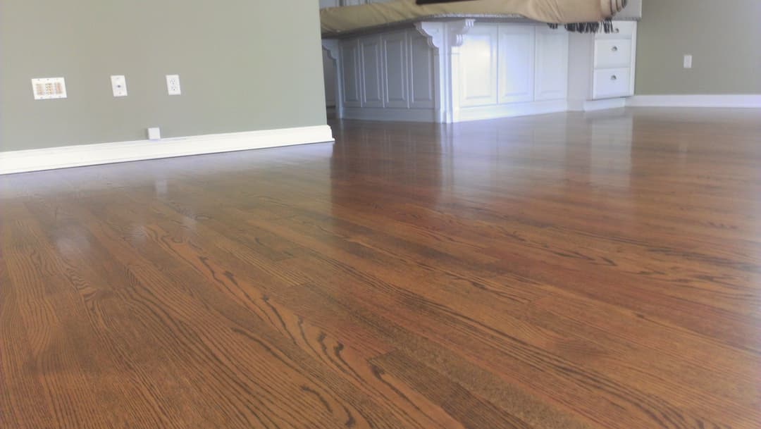 Shiny hardwood floor in a bedroom with light green walls and white furniture.