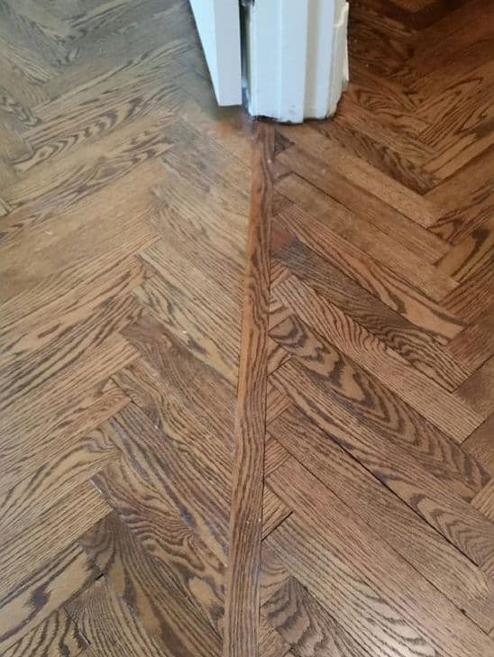Herringbone hardwood flooring with visible seam detail at the corner transition.