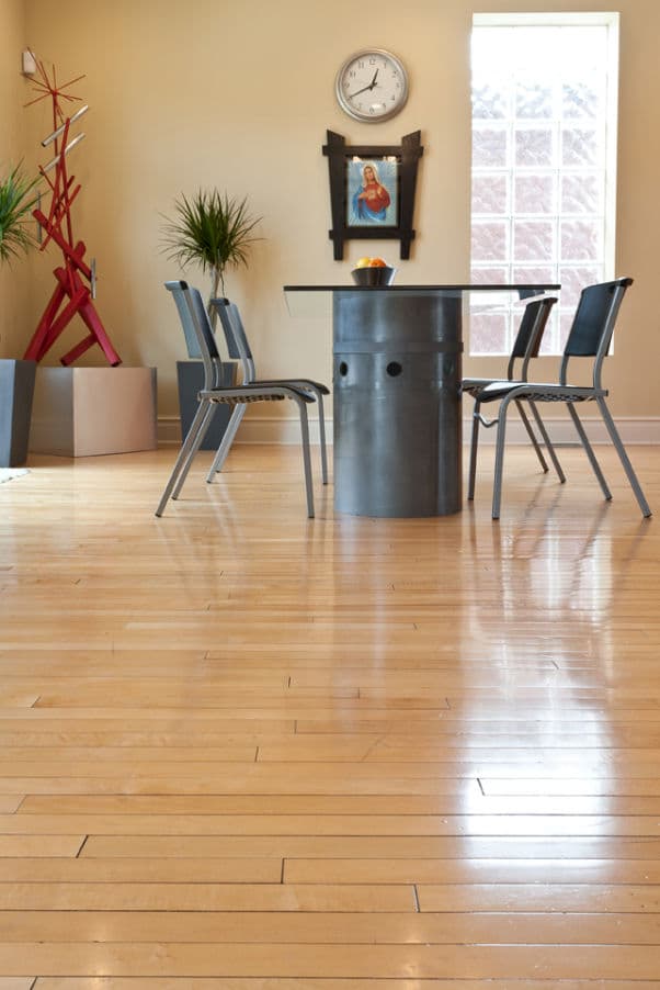 Modern dining room with metal table, black chairs, and minimalist decor. Bright wooden floors.