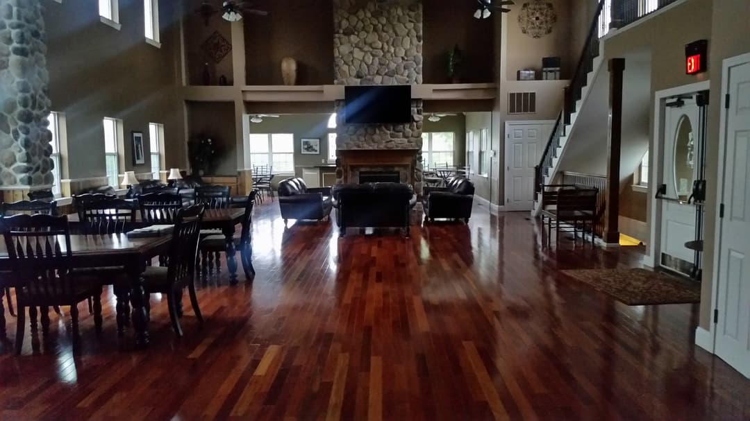 Large rustic living room with wooden floors, stone fireplace, and comfortable seating area.