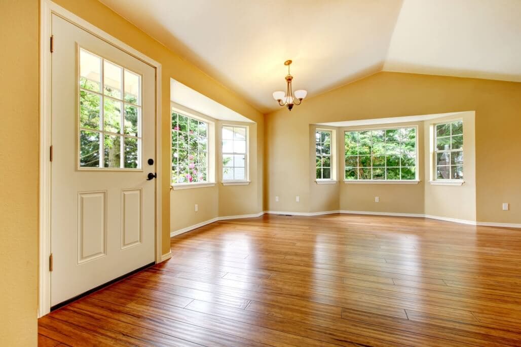 Spacious living room with hardwood floors, large windows, and natural light.