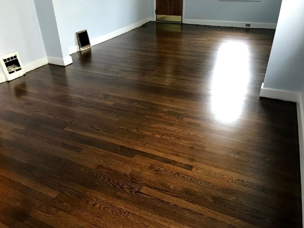 Polished brown hardwood floor in a spacious, empty room with light blue walls.