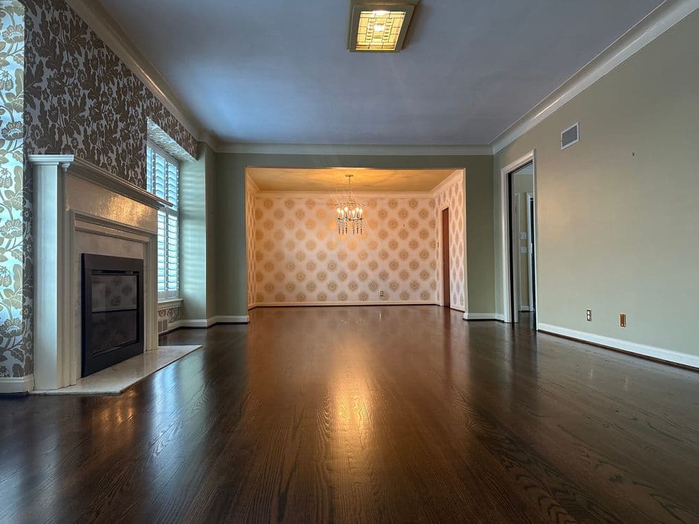 Spacious living room with hardwood floors, chandelier, and elegant wallpaper accents.