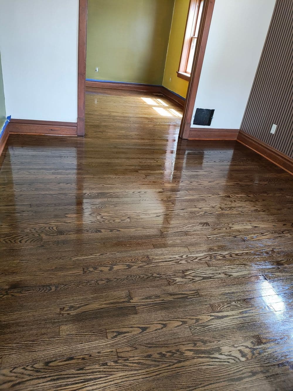 Shiny hardwood floors in a bright, empty room with green and striped walls.