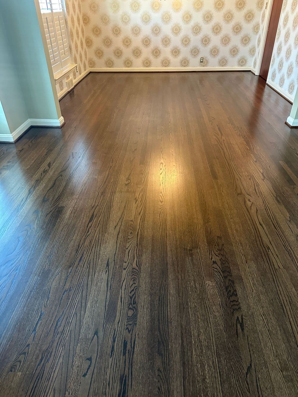 Stylish hardwood flooring in a bright, empty room with decorative wallpaper.