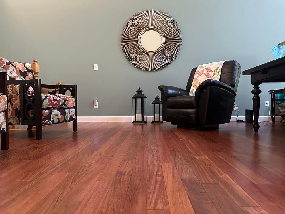 Living room with wooden floor, colorful chairs, mirror, and cozy seating area.
