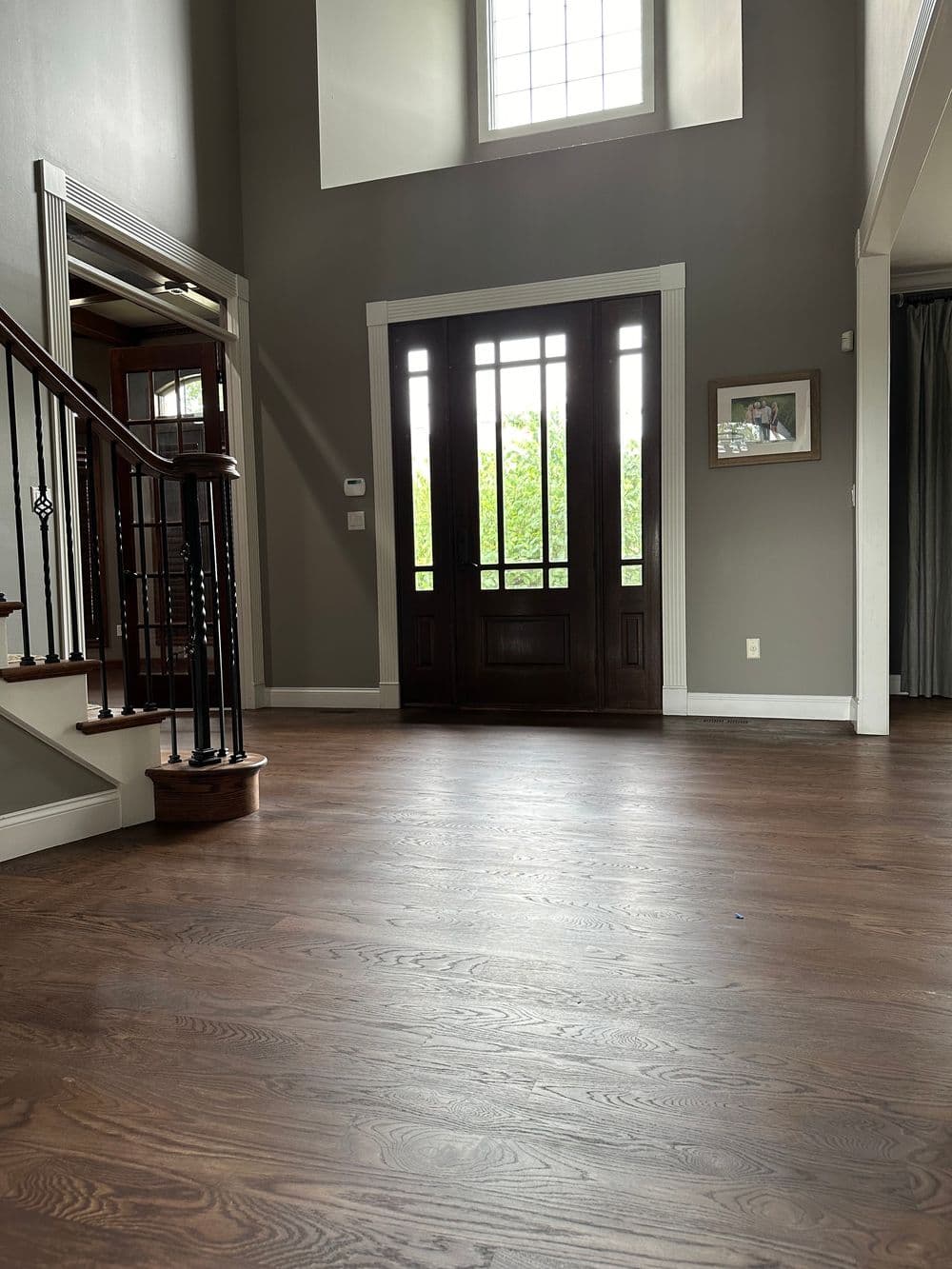 Spacious entryway with hardwood floors, large windows, and elegant staircase design.