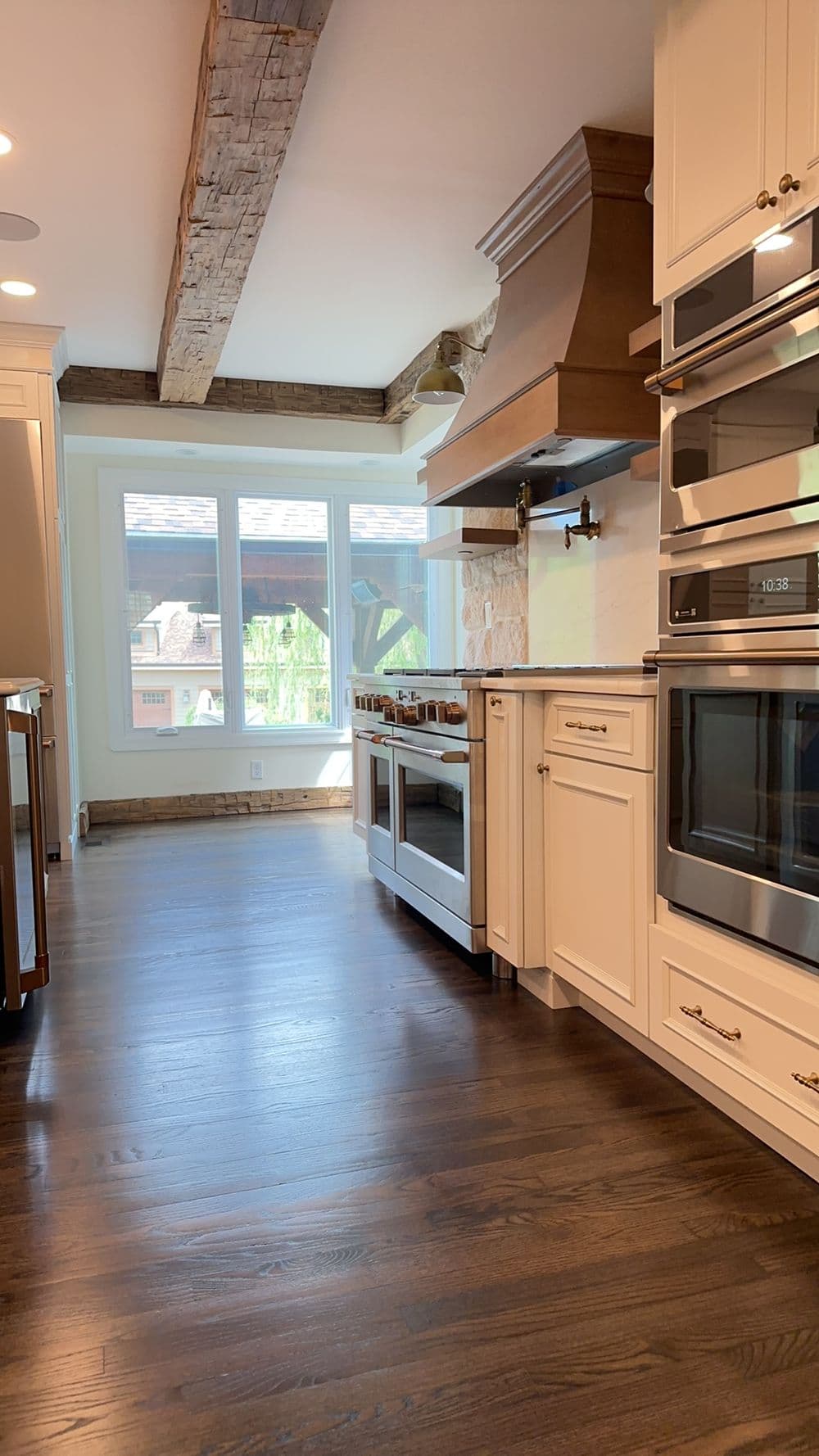 Modern kitchen with wooden beams, stainless steel appliances, and large windows for natural light.