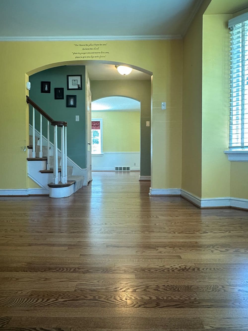 Bright interior with wood floors, yellow walls, arched doorways, and inviting natural light.